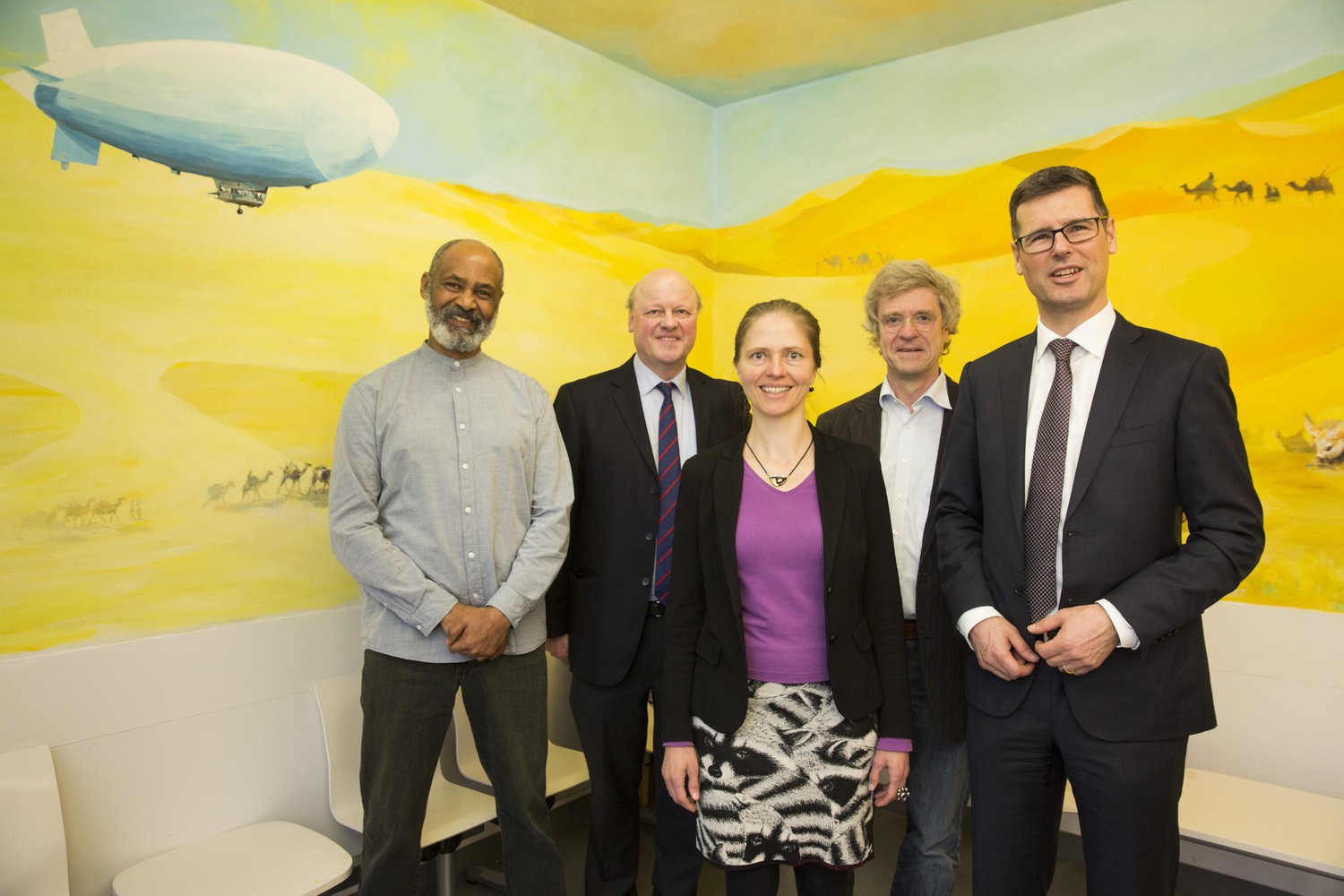 Das neue Wandbild des Künstlers Solomon Wija (li.) mit Wüstenszene schmückt nun einen Wartebereich in der UKL-Kinderklinik. Zur Übergabe der von Porsche Leipzig finanzierten Arbeit an Klinikdirektor Prof. Wieland Kieß (2.v.r.) war der kaufmännische Geschäftsführer Dr. Joachim Lamla (re.) gekommen. Kerstin Sommerfeld (Mi.) und Marc Christian Kyewski (2.v.l.) vom Vorstand der Stiftung Kinderklinik Leipzig hatten zu Jahresbeginn die Spende des Unternehmens entgegennehmen dürfen.